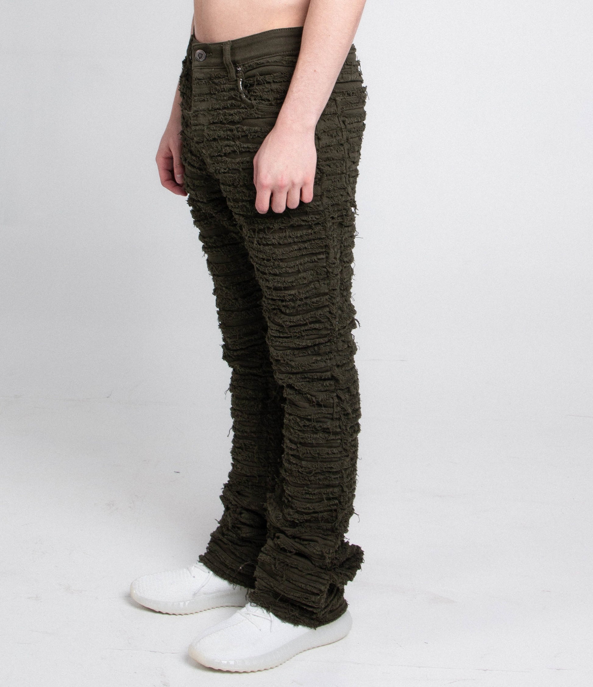 Side view of green fitted jeans with five pockets.