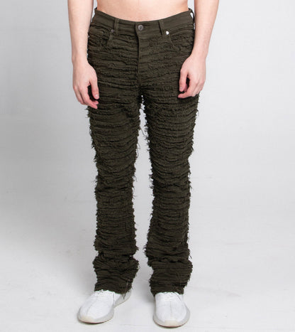 Front view of green stacked jeans with frayed inseam.