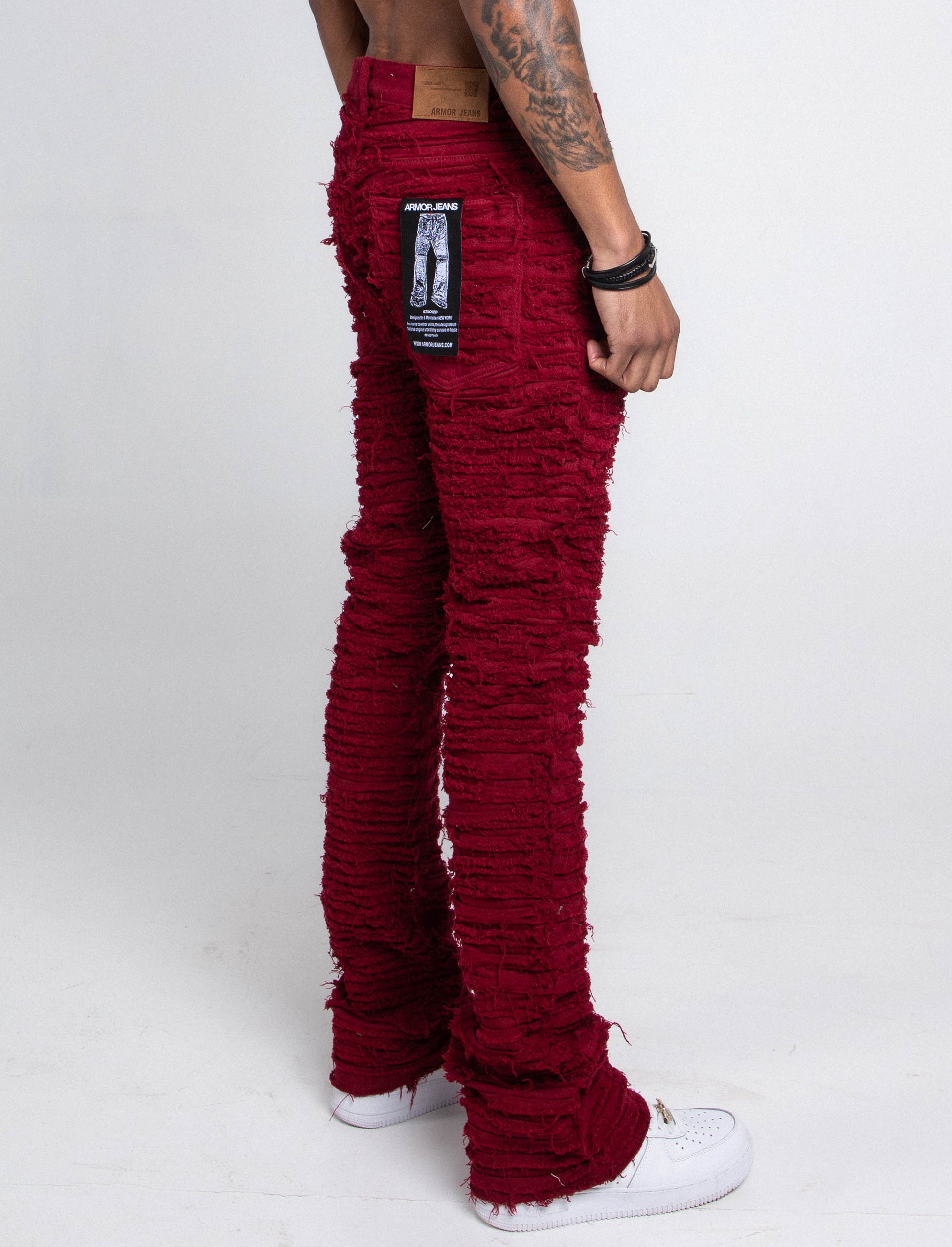 Side view of red stacked jeans with frayed inseam.