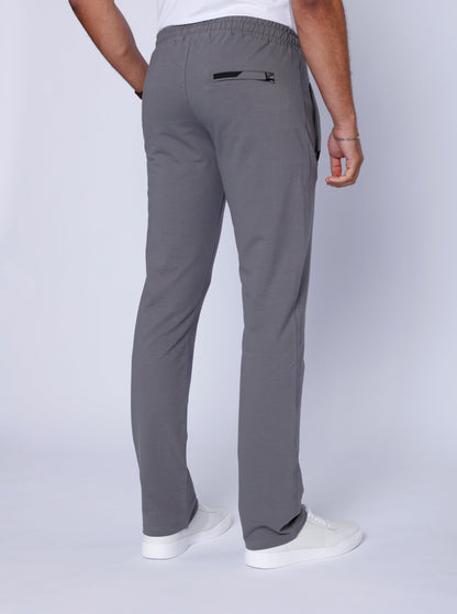 Detail of grey pants featuring hand in pocket and zipper pocket.