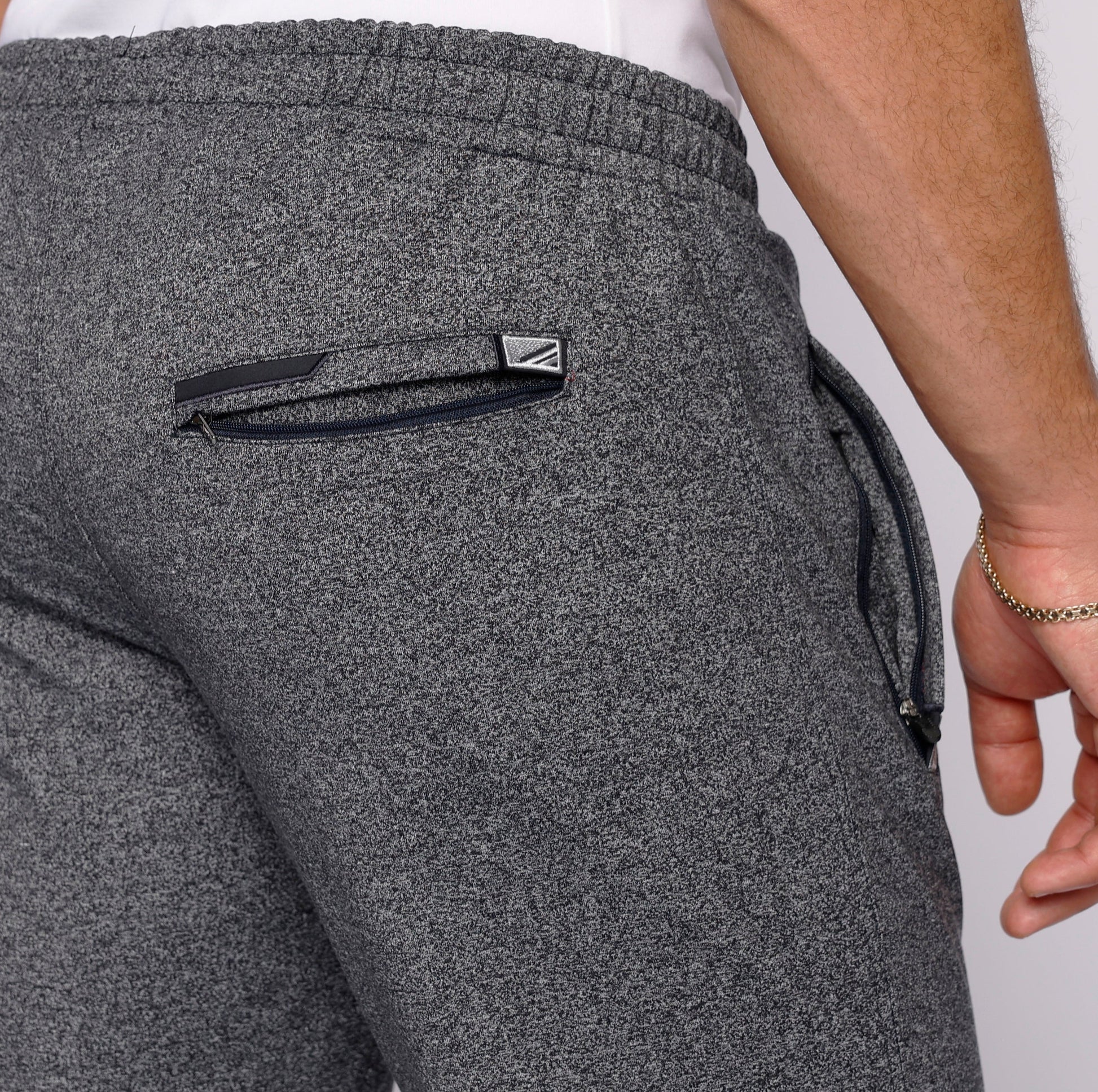 Detail shot of gray sweatpants with a back pocket and zipper.