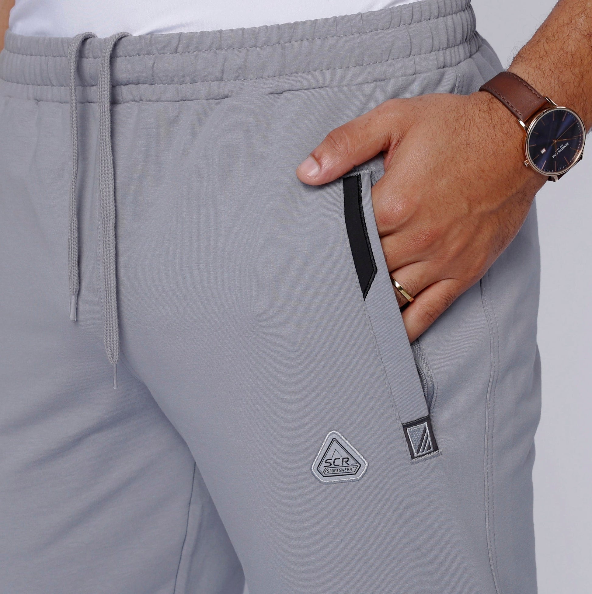 Detail shot of gray sweatpants with zipper pockets and drawstring waist.