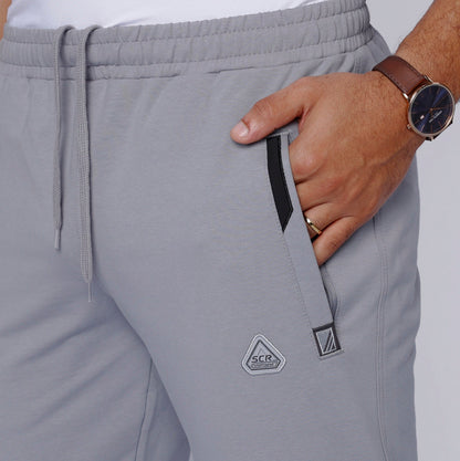 Detail shot of gray sweatpants with zipper pockets and drawstring waist.