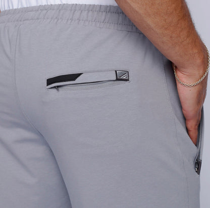 Close-up detail of gray sweatpants highlighting zipper pockets.