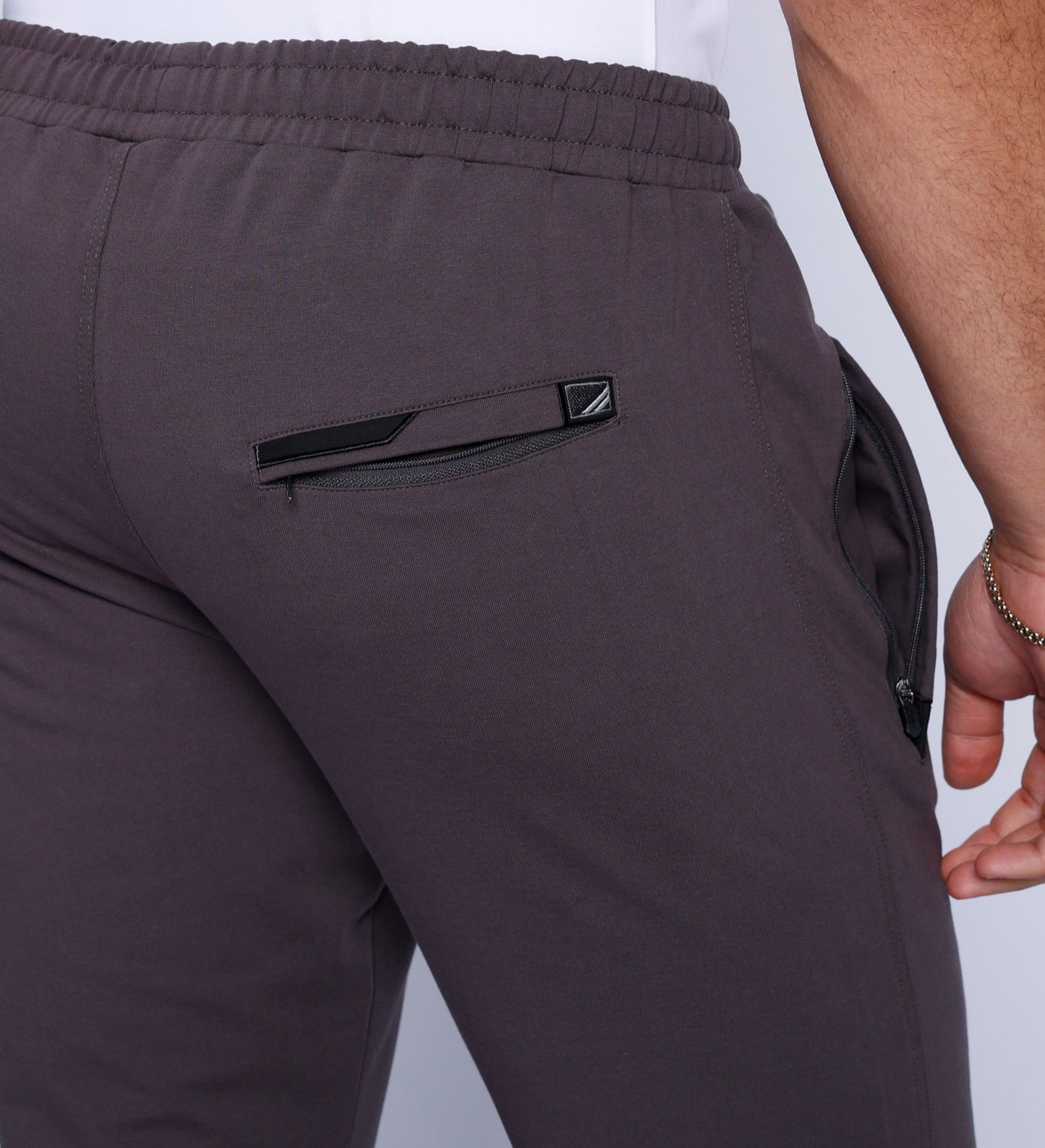 Detail view of grey joggers featuring a zipper pocket and elastic waistband.