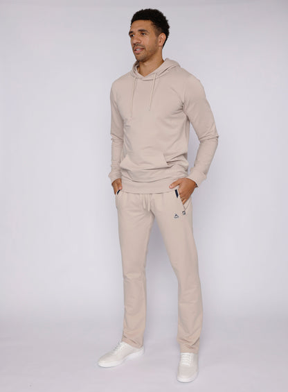Lifestyle shot of a man in beige sweatpants and hoodie.