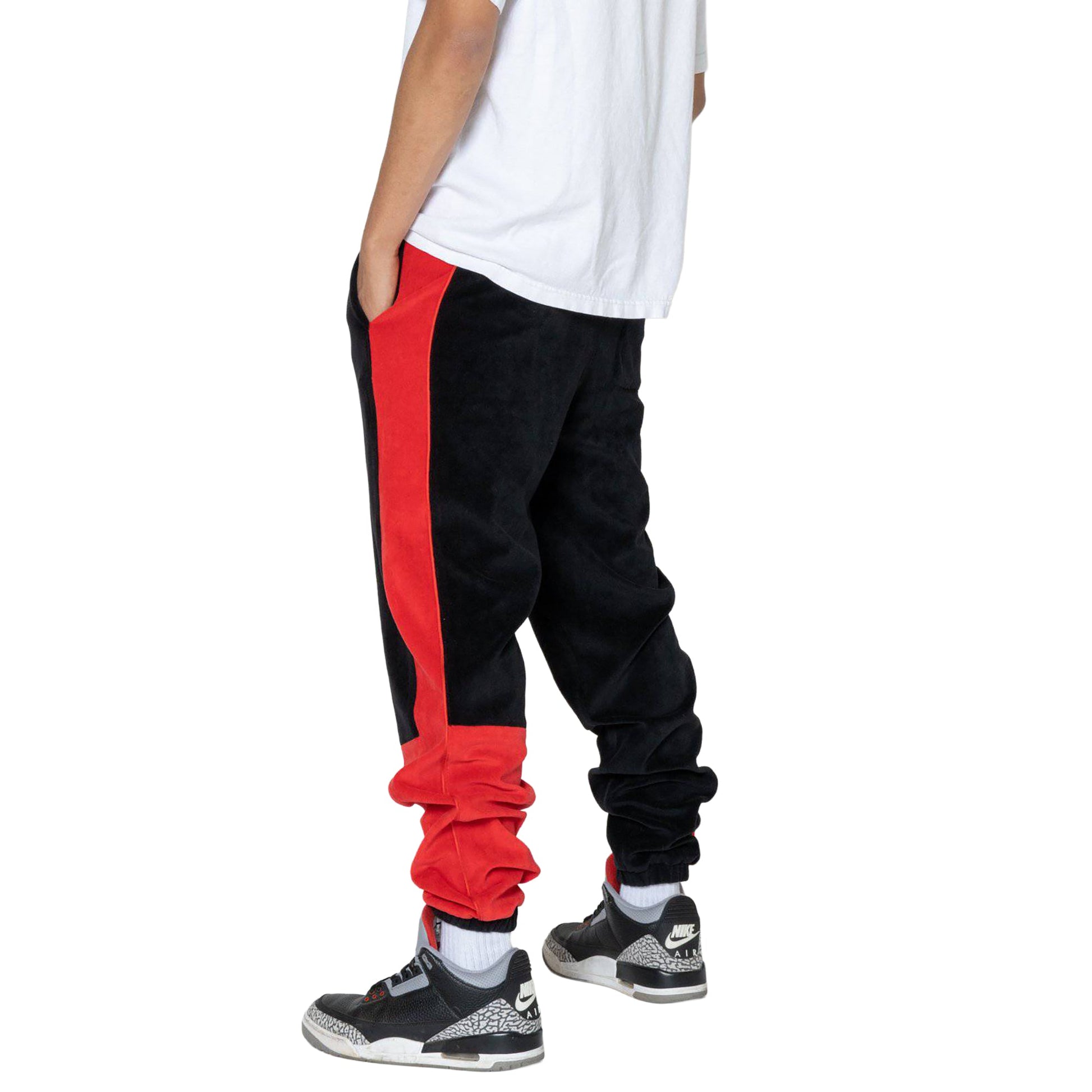 Back view of black joggers with elastic waistband and red side stripes.