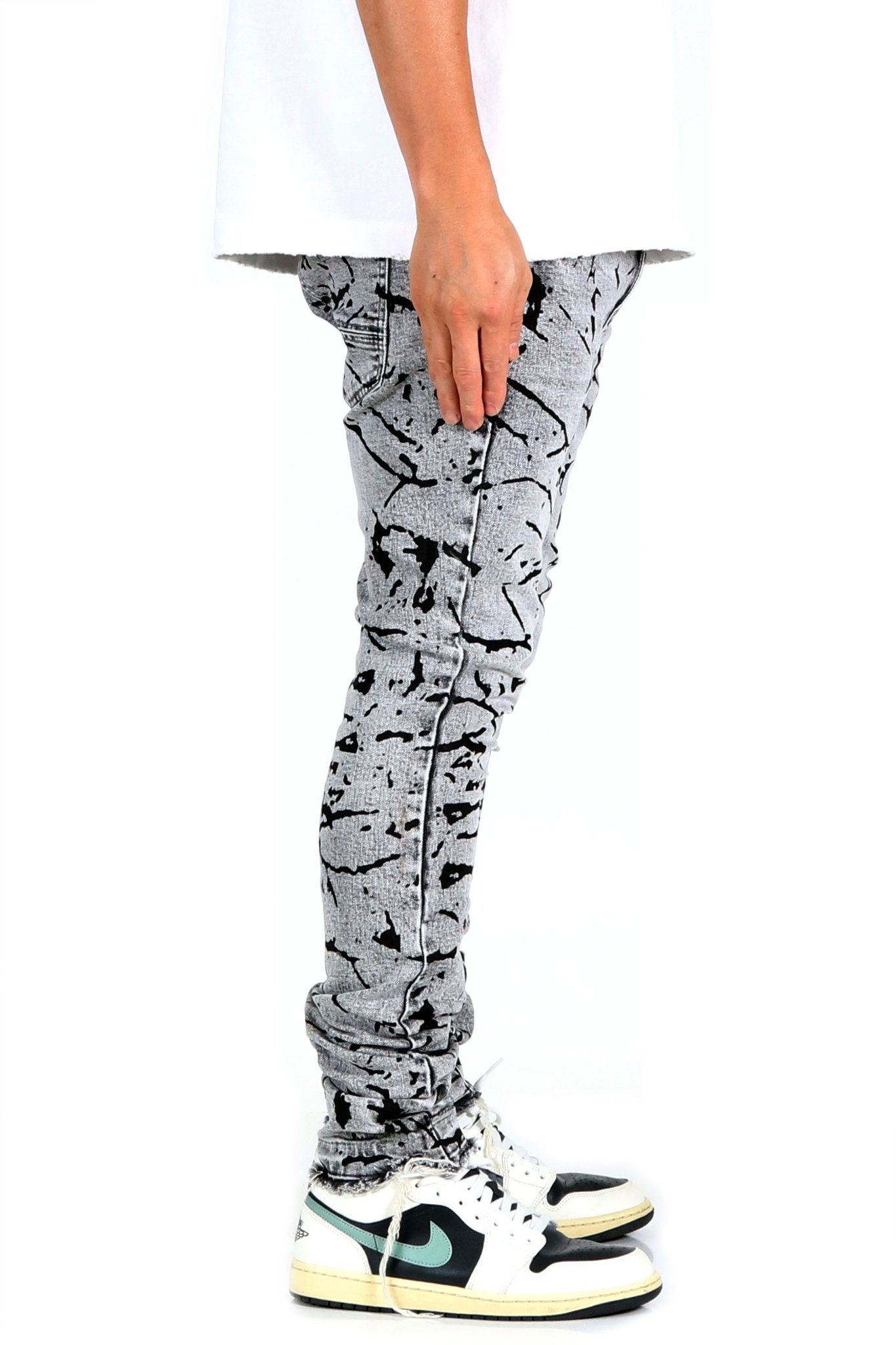Side view of black and white graphic print skinny denim pants.