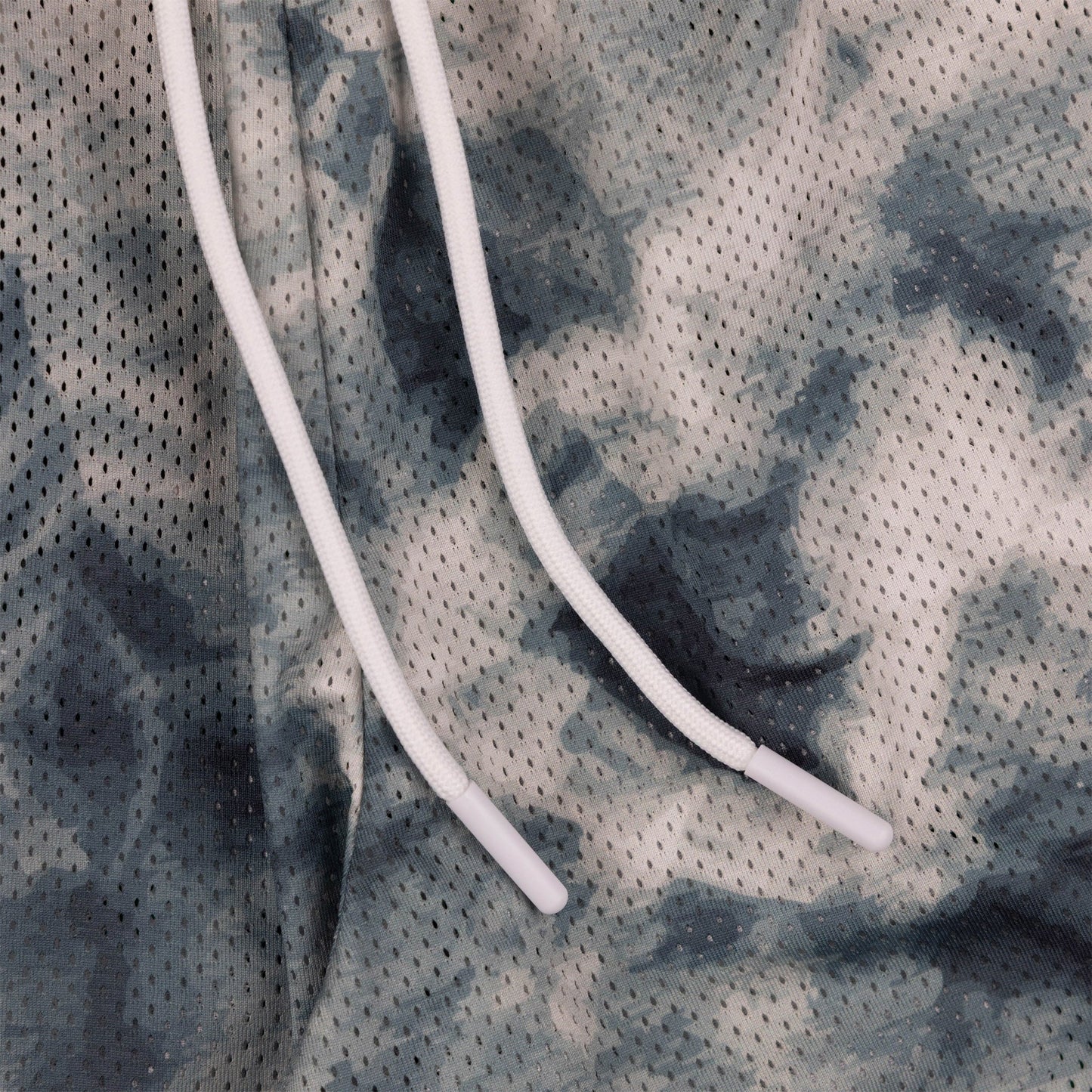 Close-up of the drawstring on the tie-dye shorts in grey and white.