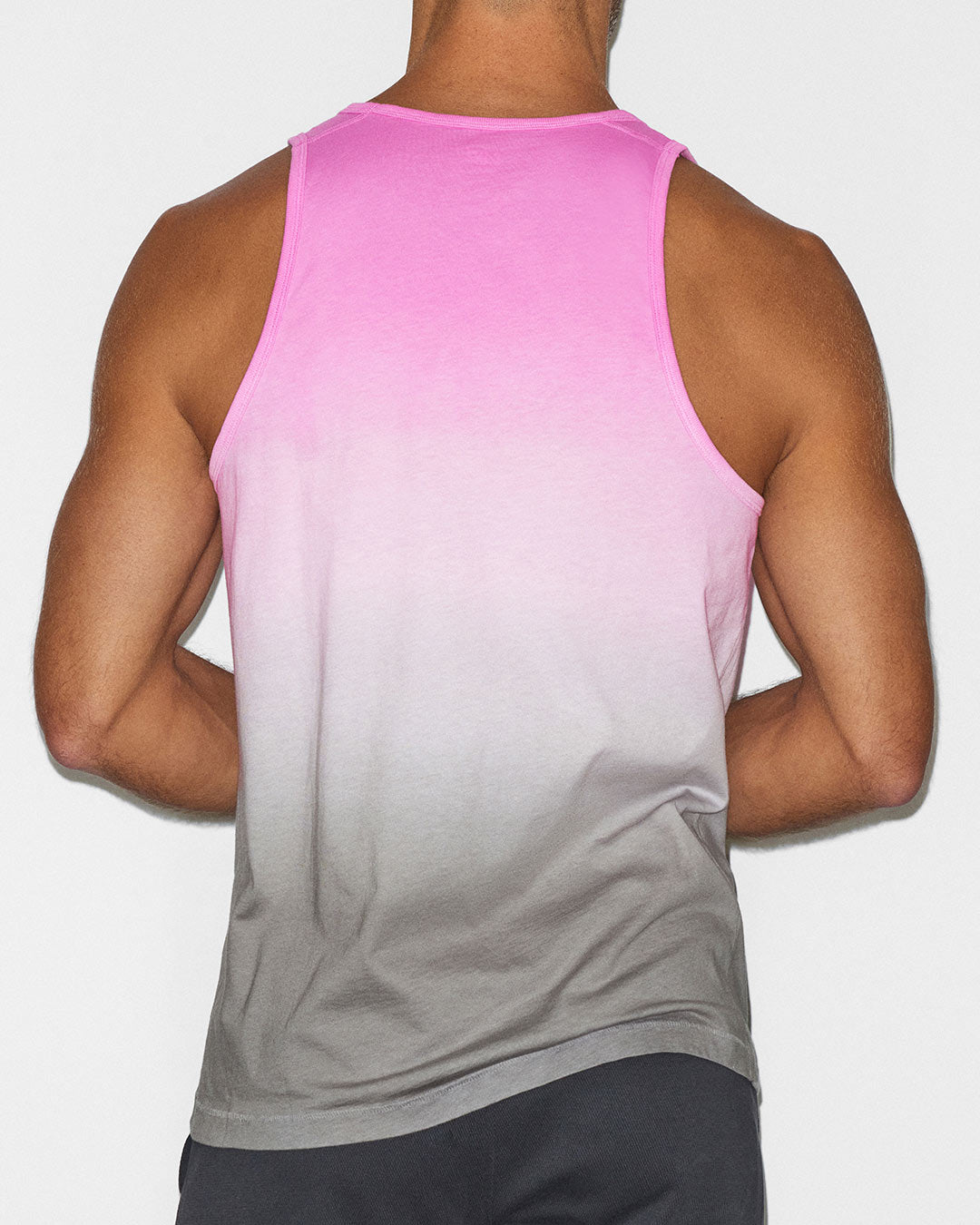 Lifestyle shot of a man in a pink tank outdoors.