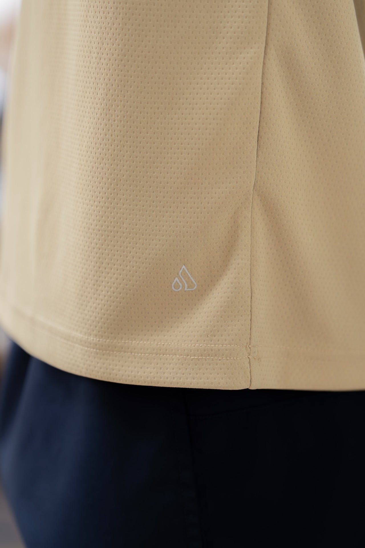 Close-up detail of the beige Journey Tee fabric, highlighting smooth texture.