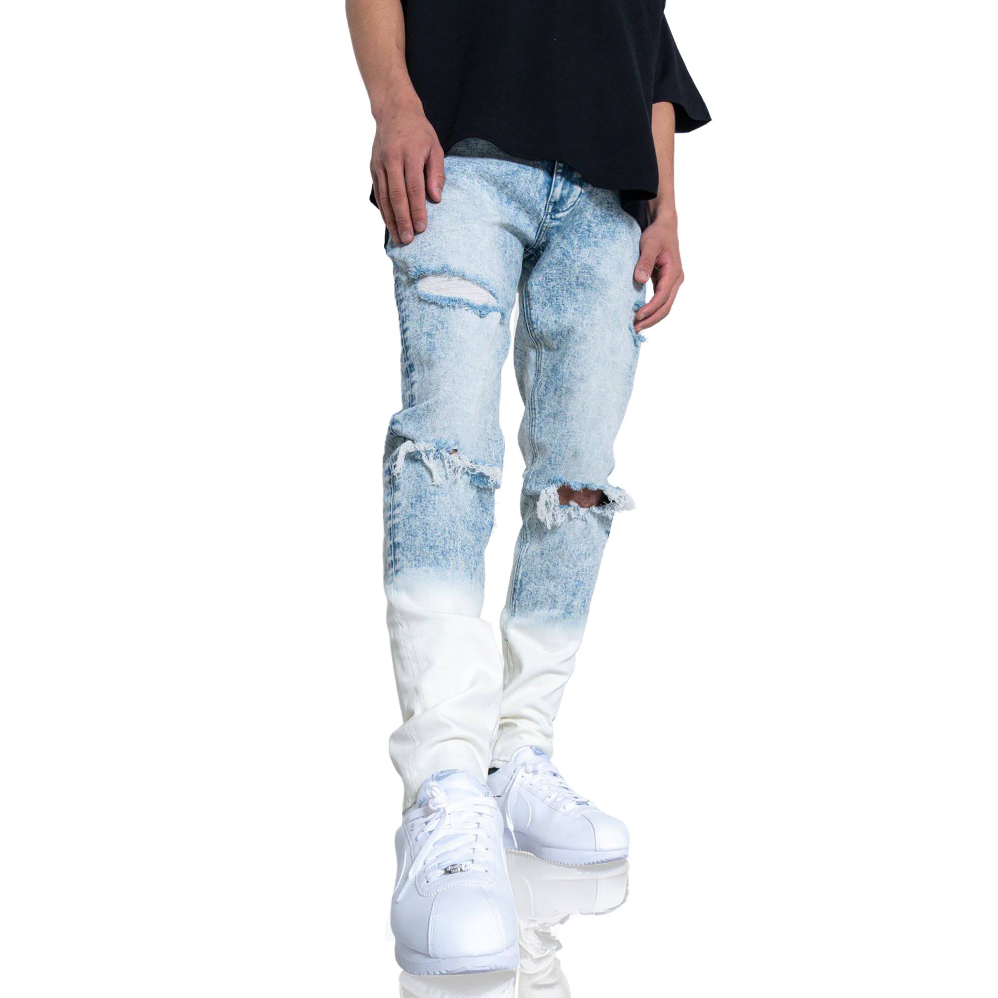 Close-up of blue jeans showing ripped knees and faded design.
