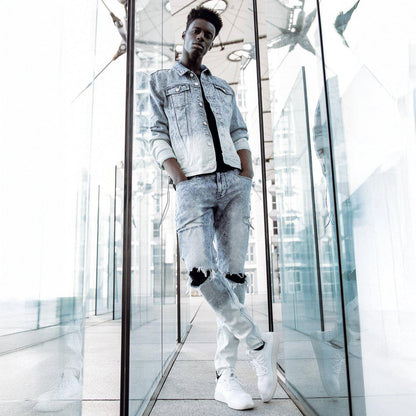 Lifestyle shot of blue slim tapered jeans with rips outdoors.
