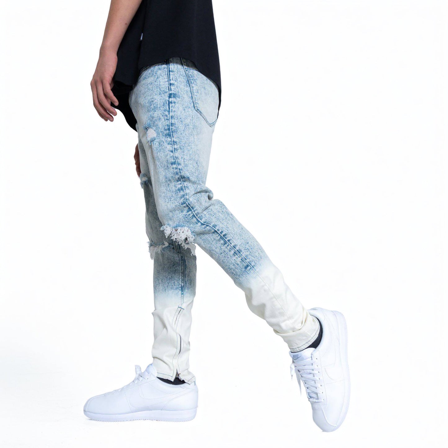 Side view of a man wearing blue faded jeans and sneakers.