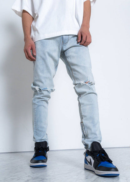 Lifestyle image of light blue jeans showcasing ripped knees on a white background