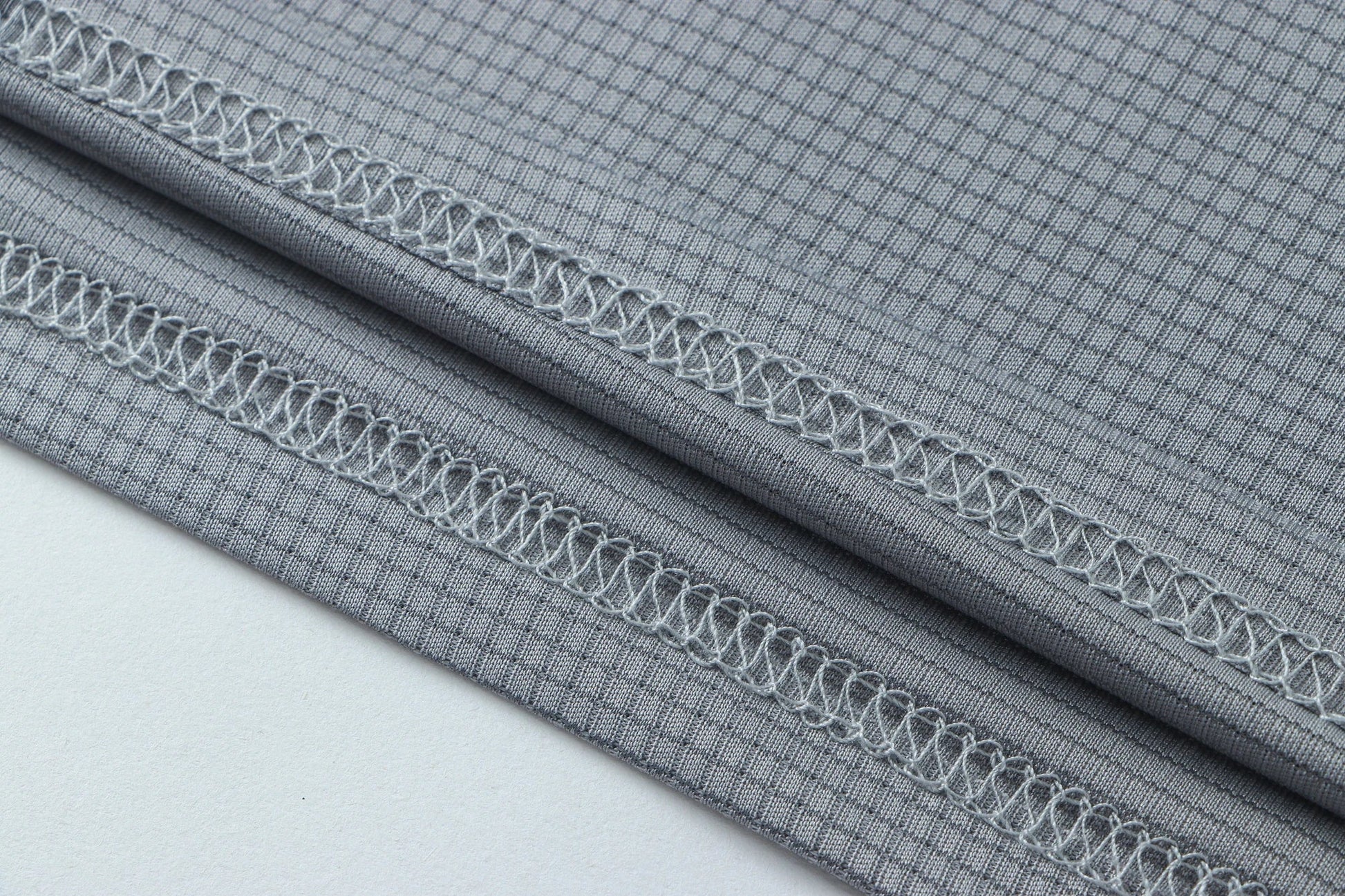 Detail shot of gray fabric showcasing fine stitching and a smooth surface.