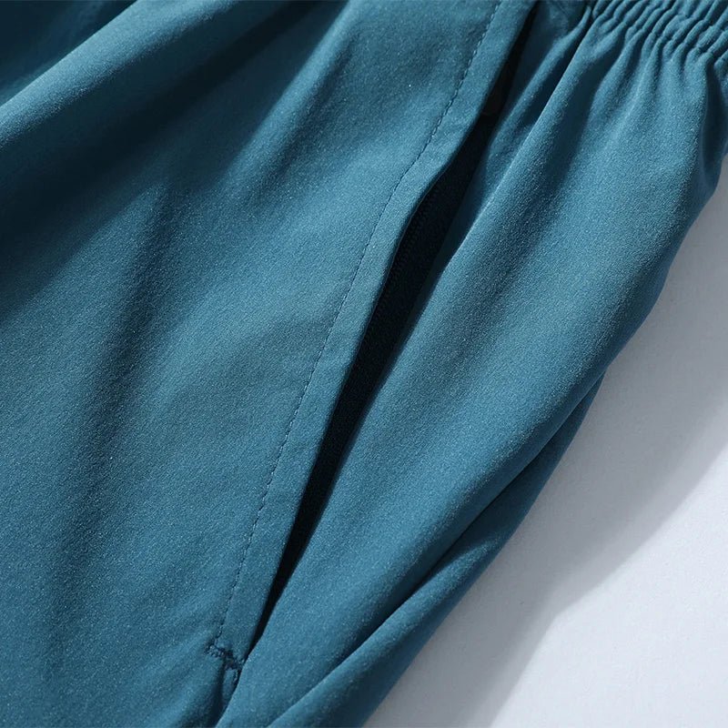 Detail view of teal running shorts with elastic waistband and side pocket.