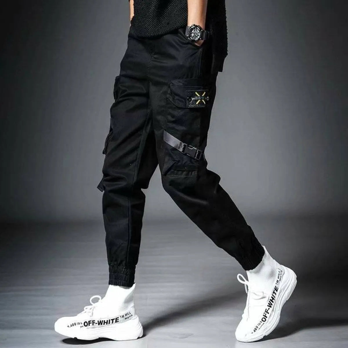 Side view of black cargo pants with branding and elastic cuffs.