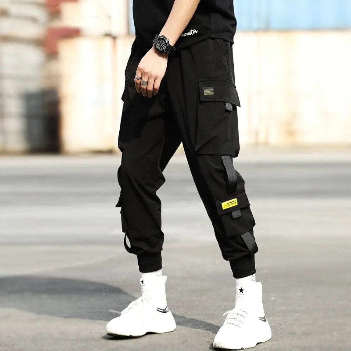 Black cargo pants with knee details and elastic cuffs, lifestyle shot.