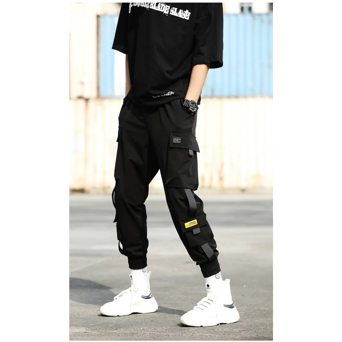 Black cargo pants featuring multiple pockets, side view in urban setting.