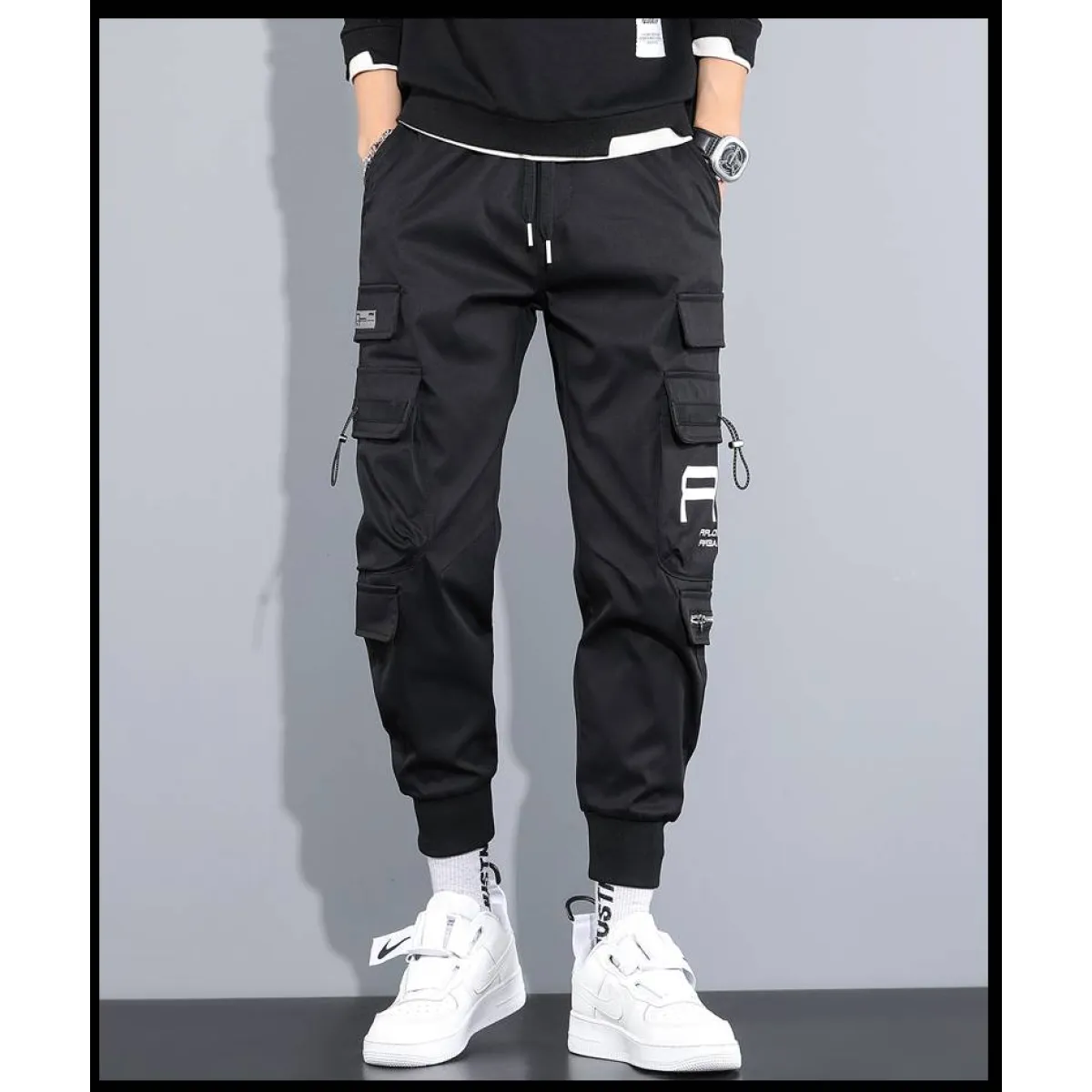 Front view of black cargo pants with cargo pockets and elastic cuffs.
