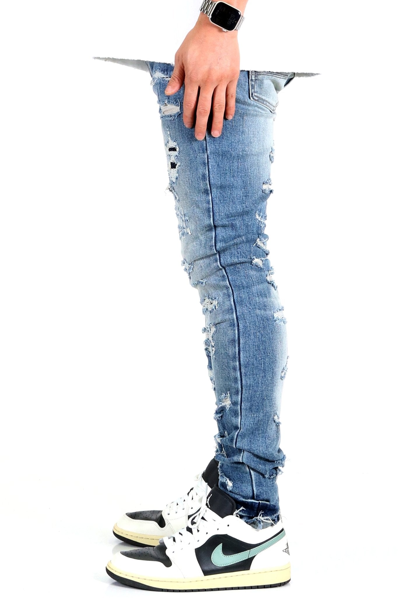 Side view of the blue distressed skinny jeans with hand in pocket.