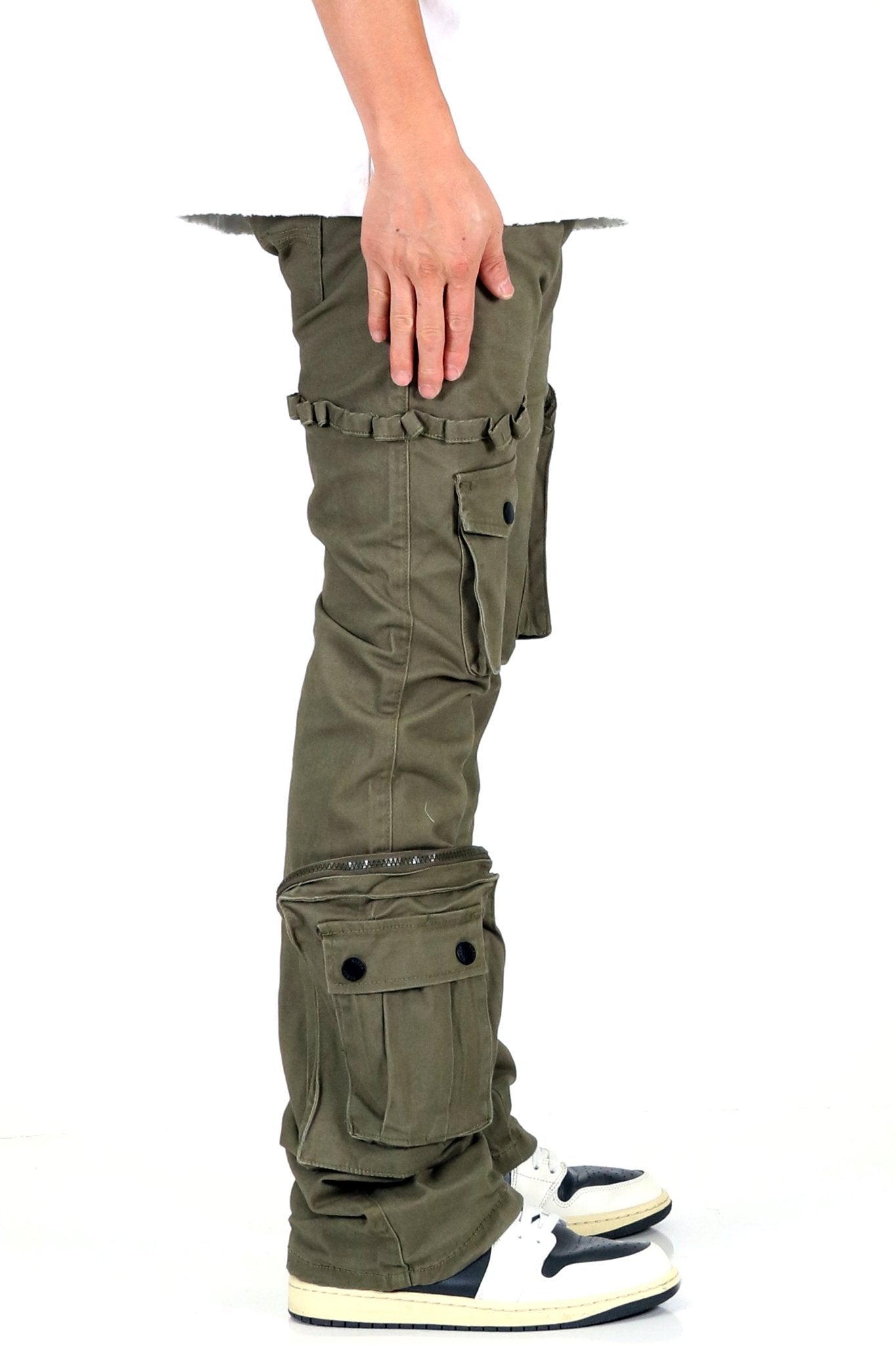Detail close-up of olive cargo pants showing hand inside pocket and cargo style.