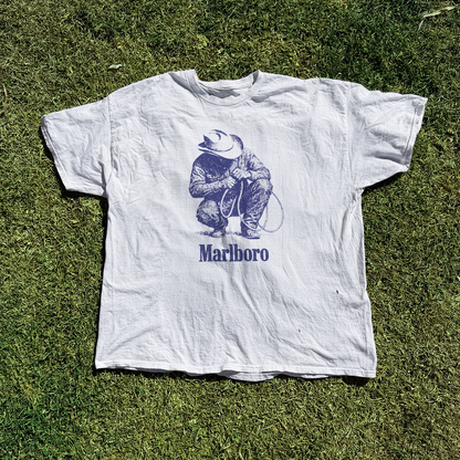 Graphic white t-shirt laid flat on grass.