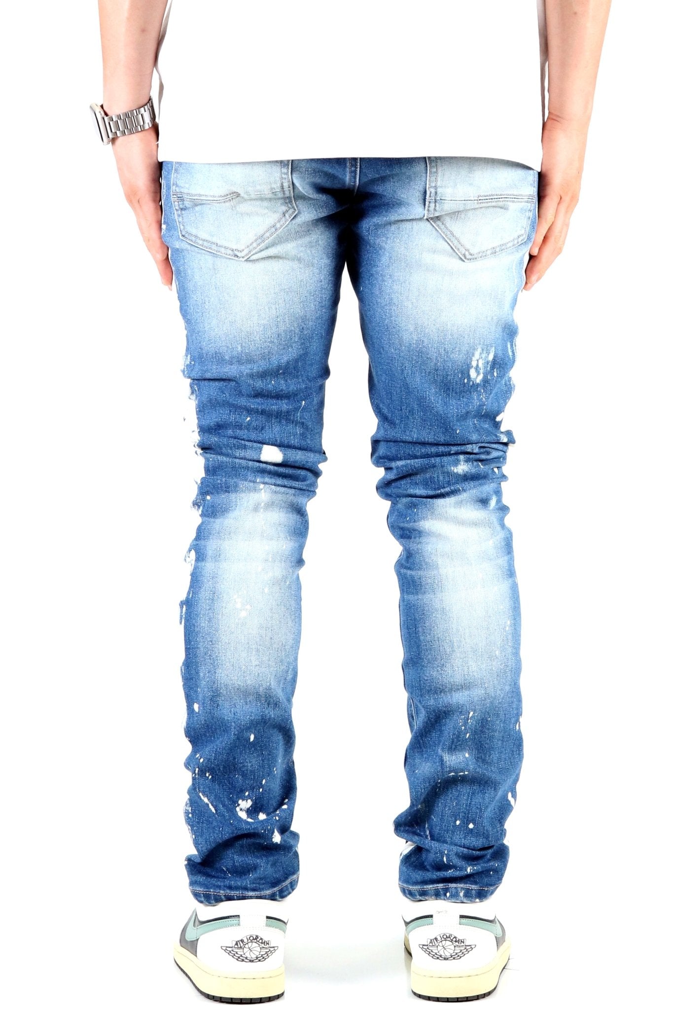Back view of blue distressed skinny jeans featuring faded areas.