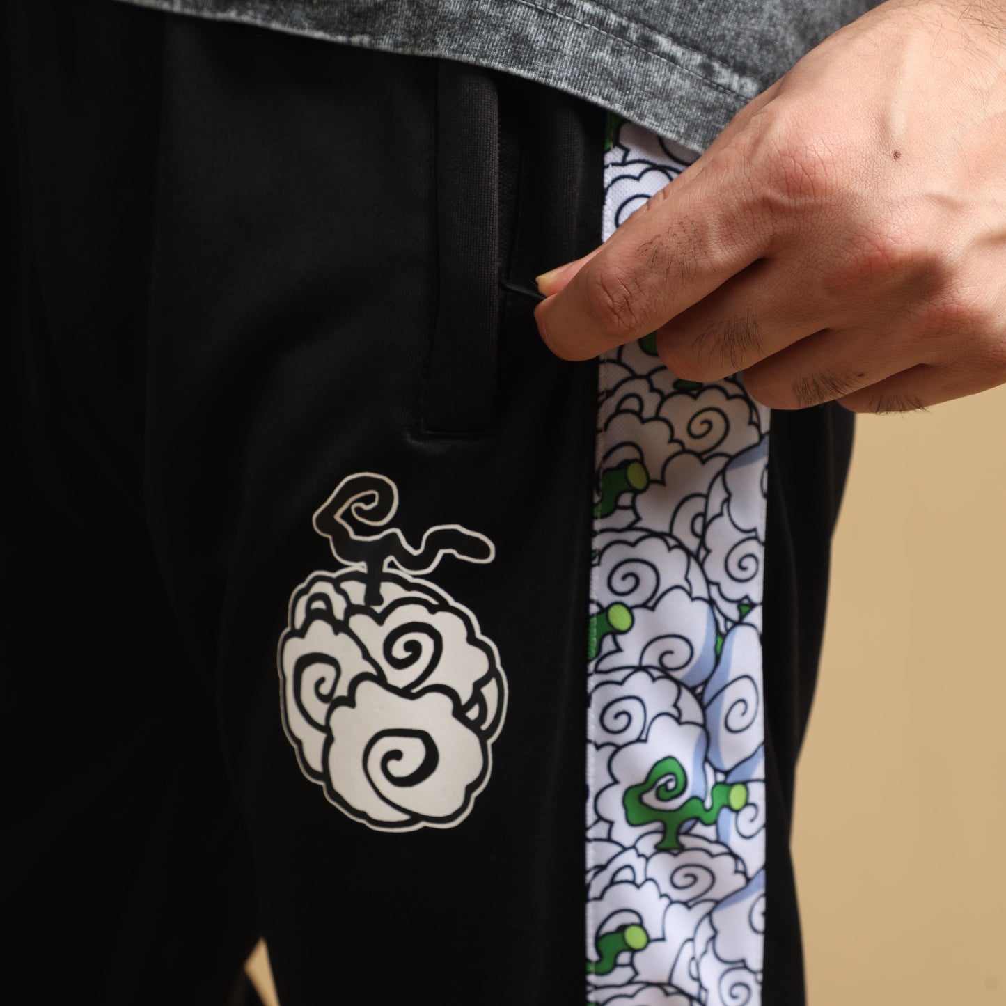 Close-up of black pants with embroidery and patterned side stripe on a solid background.