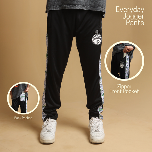 Black jogger pants with side stripes in a natural setting.