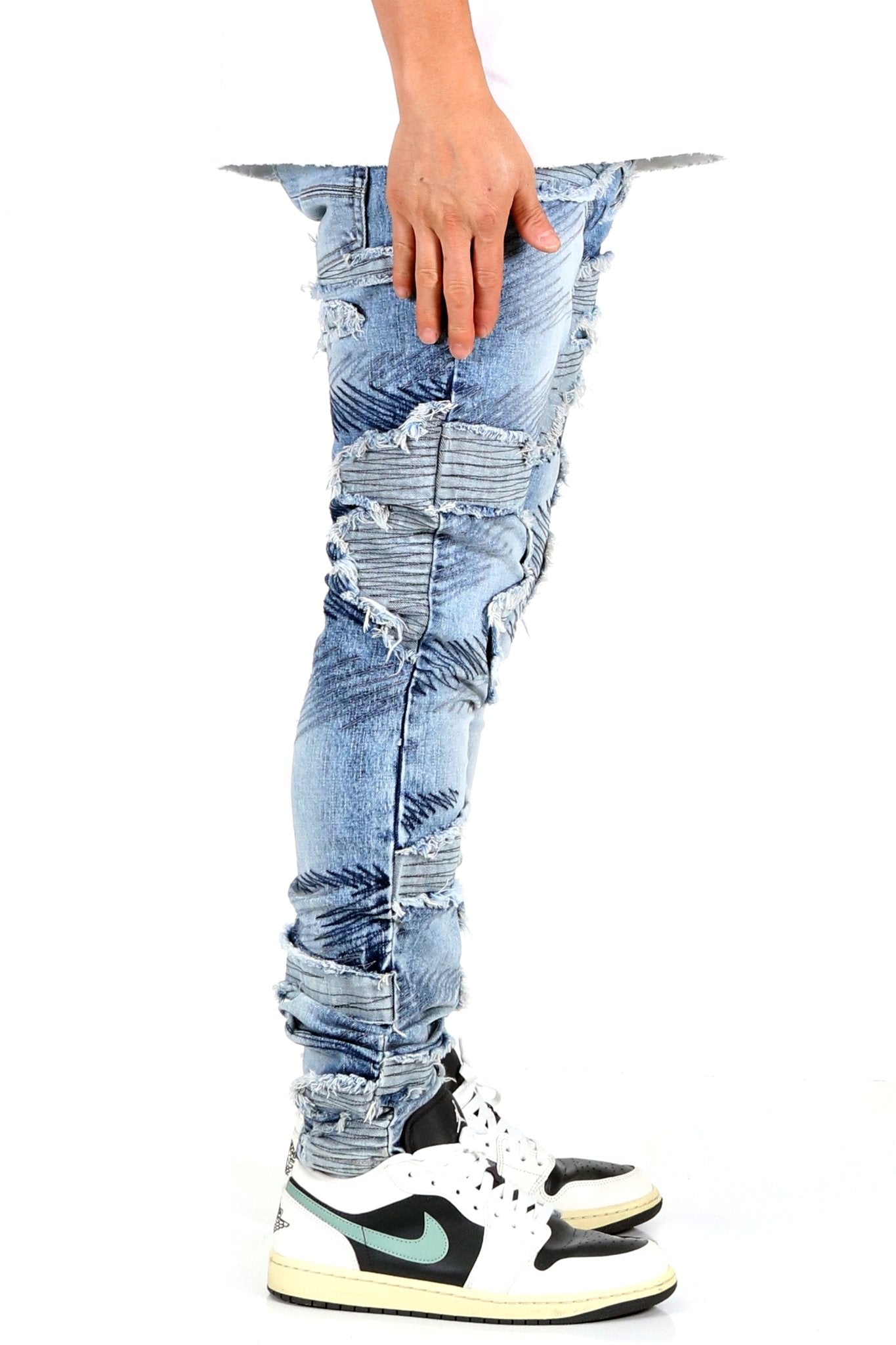 Side view of blue skinny denim pants showcasing hand placement.
