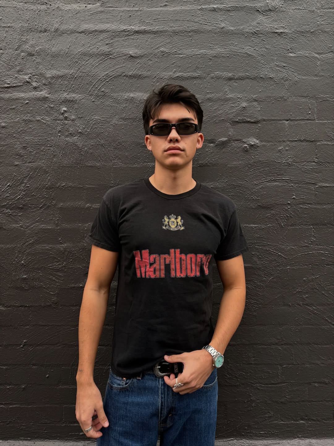 Lifestyle shot of a man in sunglasses wearing a black graphic t-shirt.